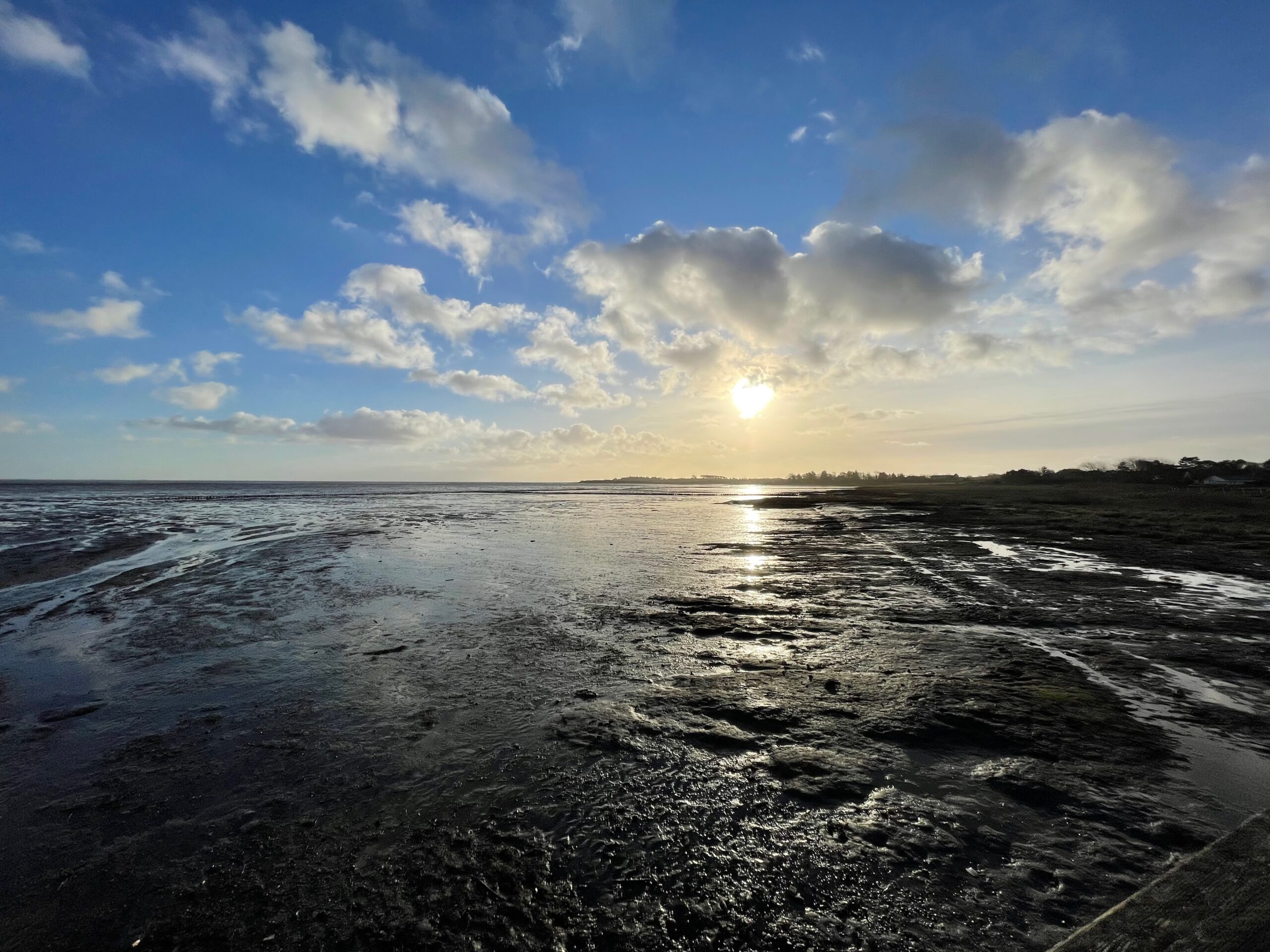 Sonnenaufgang über einer Insel im Wattenmeer. Wolken am blauen Himmel